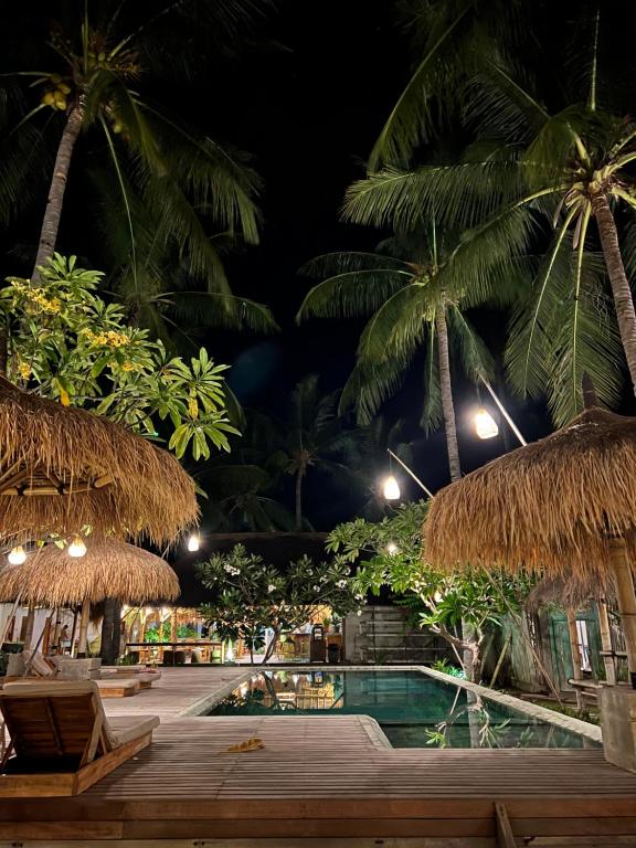 a resort with a pool and palm trees at night at Captain Coconuts Gili Air in Gili Air