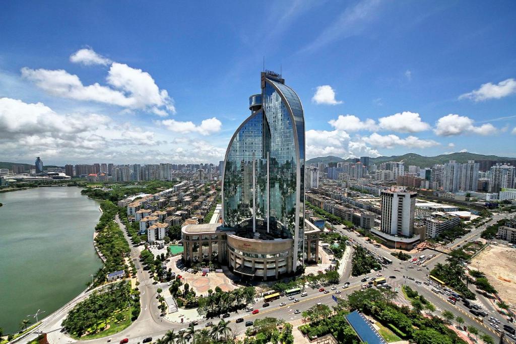 ein großes Glasgebäude in einer Stadt neben einem Wasserkörper in der Unterkunft Kempinski Hotel Xiamen in Xiamen
