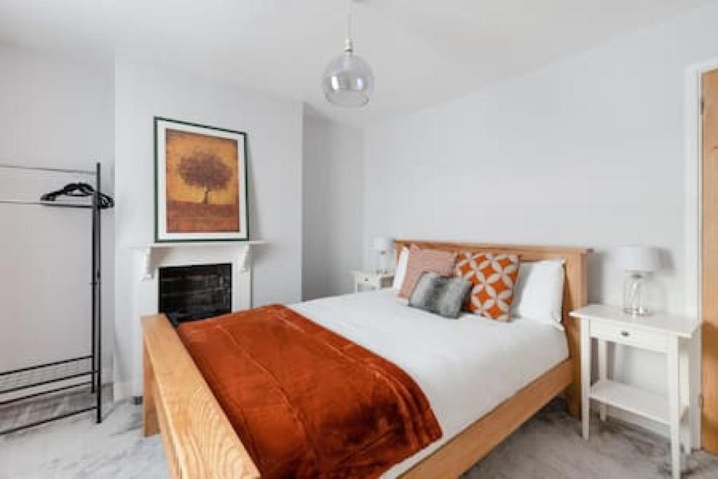 a white bedroom with a bed and a fireplace at Cosy 2-bedroom house in Croydon in Croydon