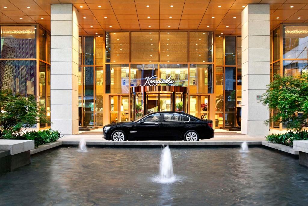 ein Auto, das vor einem Gebäude mit einem Brunnen parkt in der Unterkunft Kempinski Hotel Chongqing in Chongqing