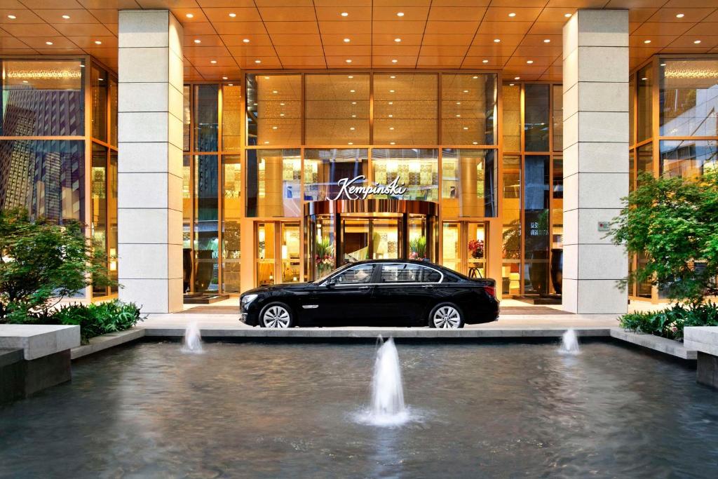a car parked in front of a building with a fountain at Kempinski Hotel Chongqing in Chongqing