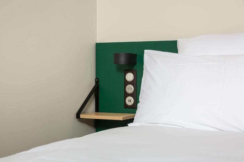 - un lit avec une tête de lit verte et un oreiller blanc dans l'établissement Best Western 11BAUER Paris Saint-Ouen, à Saint-Ouen