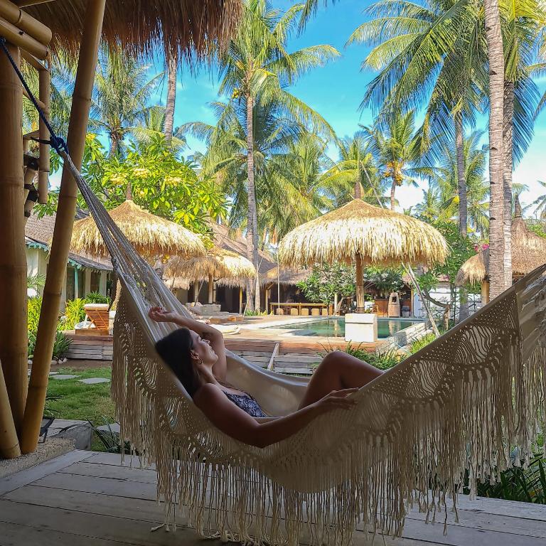 a woman laying in a hammock at a resort at Captain Coconuts Gili Air in Gili Air