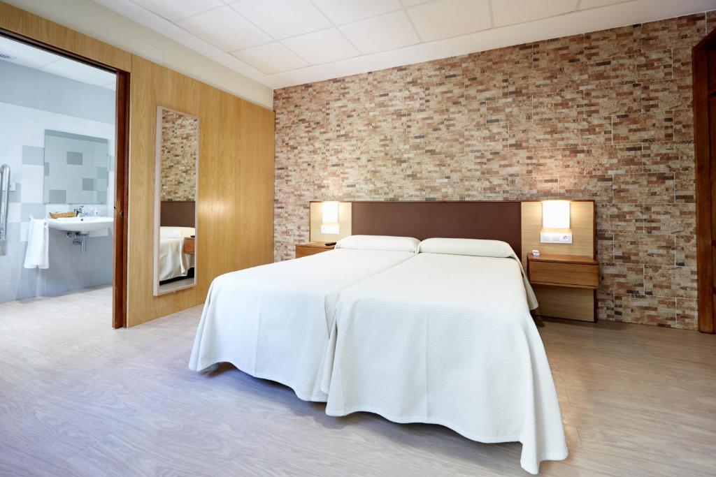 a large white bed in a room with a brick wall at Hostal Campo Nuevo in Sanlúcar de Barrameda