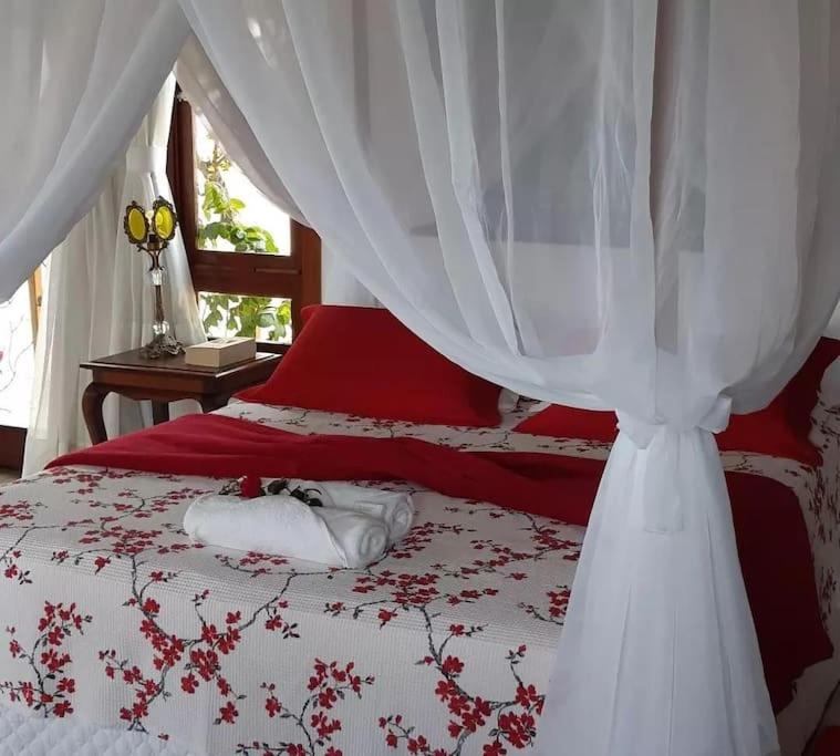 a bedroom with a red and white bed with a canopy at Chalé romântico, com vista panorâmica, para Casais in Monte das Gameleiras