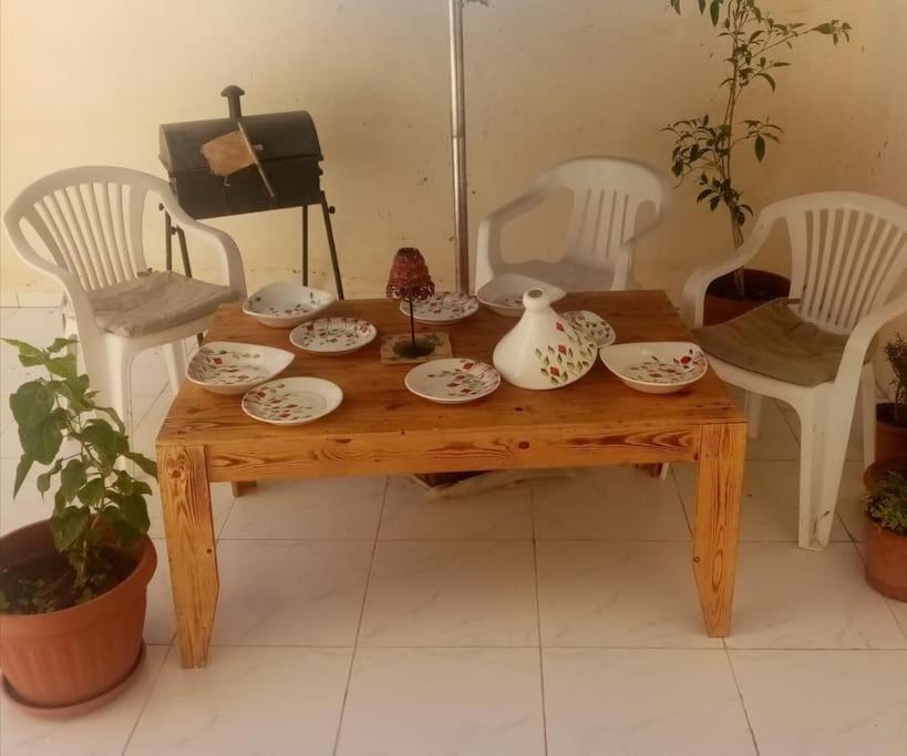 a wooden table with plates and vases on it at Coin chaleureux coté plage in Hammam Sousse