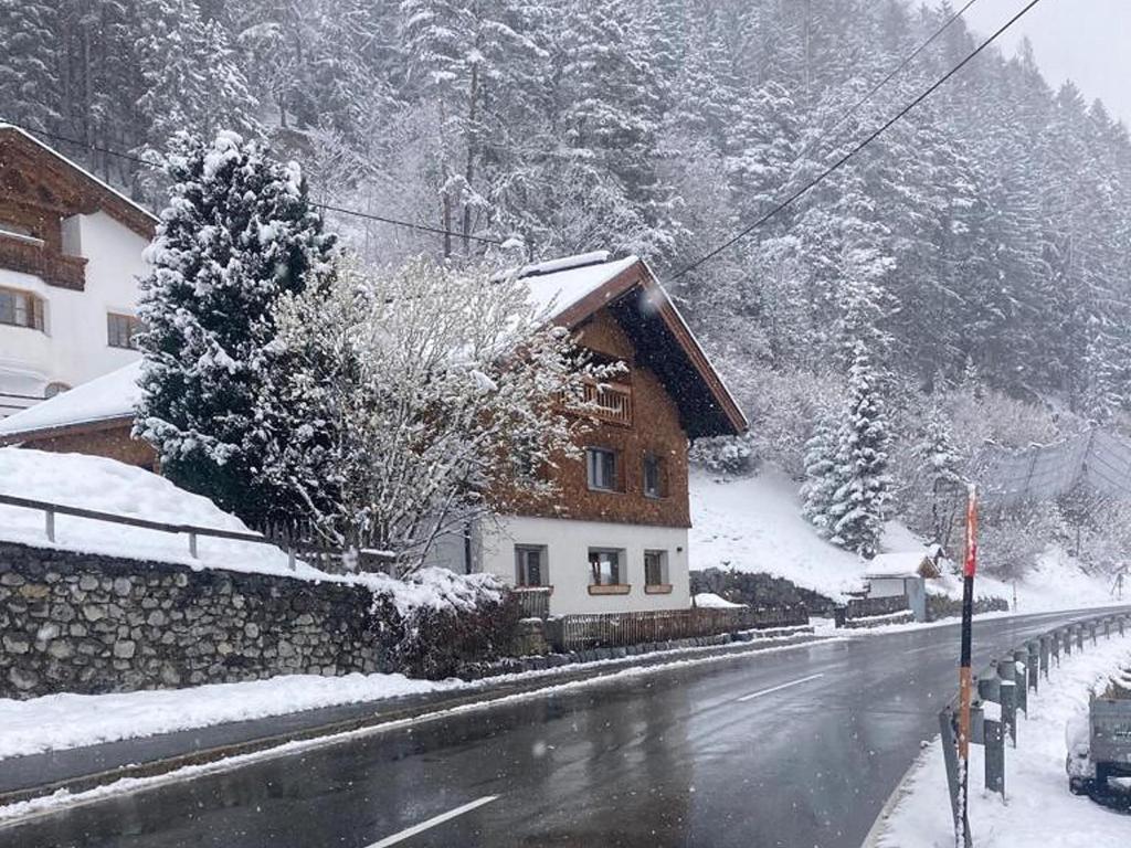 una casa al lado de una carretera cubierta de nieve en Apart Loisa en Pettneu am Arlberg