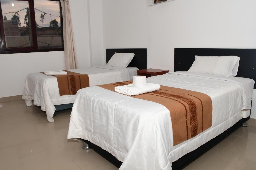 two beds in a hotel room with white sheets at LA CASA DEL TURISTA in Chachapoyas