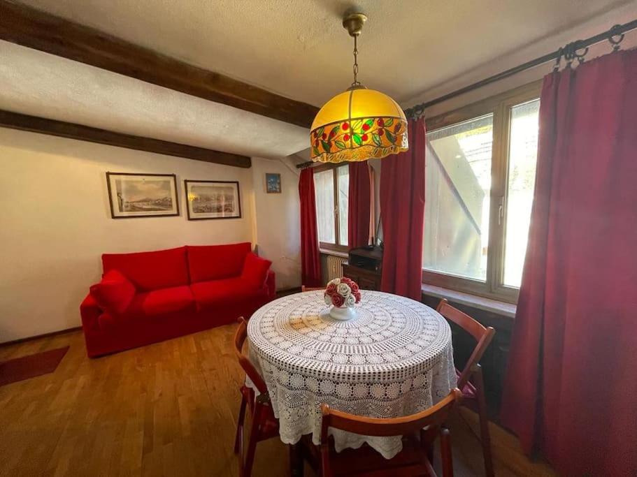 a living room with a table and a red couch at Grazioso monolocale in Borgata Sestriere