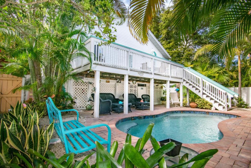 a pool with two blue chairs next to a house at Sail Away Cottage in Bradenton Beach