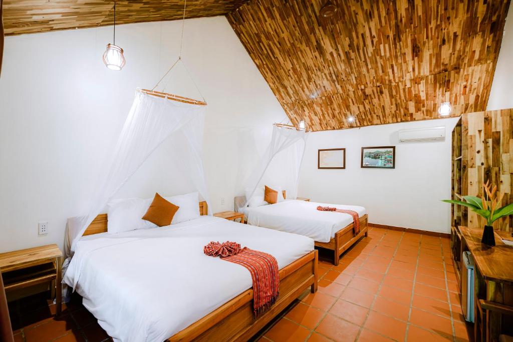 a bedroom with two beds and a wooden ceiling at La Mer Resort, Phú Quốc in Phú Quốc