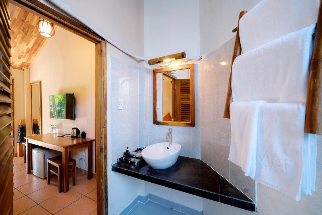 a bathroom with a sink and a mirror at La Mer Resort, Phú Quốc in Phú Quốc