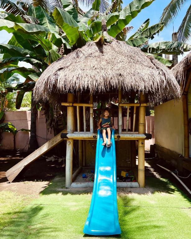 a child sitting on top of a blue slide at Captain Coconuts Gili Air in Gili Air