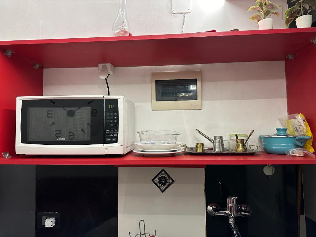 un four micro-ondes assis sur un comptoir rouge dans une cuisine dans l'établissement Apartment in Zamalek, au Caire