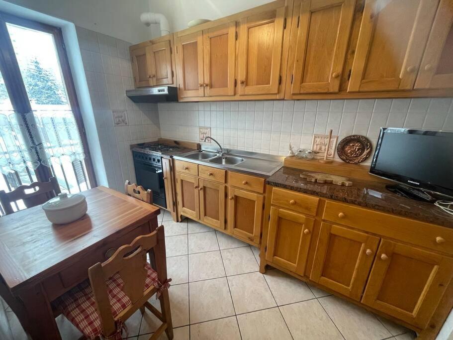 a kitchen with wooden cabinets and a sink and a table at Bilocale a Pragelato in Pragelato