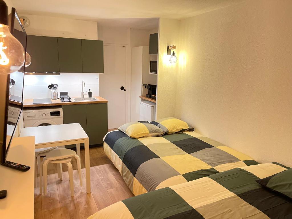 une chambre avec deux lits, une table et une cuisine dans l'établissement T2D Apartment - Suite TVR proche Disneyland Paris, à Bussy-Saint-Georges