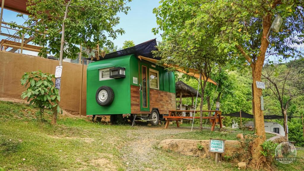 a green tiny house parked in a yard at UCM Adventure Park in San Mateo