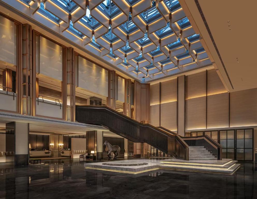 a lobby with a staircase and a glass ceiling at Empark Prime Hotel Beijing in Beijing