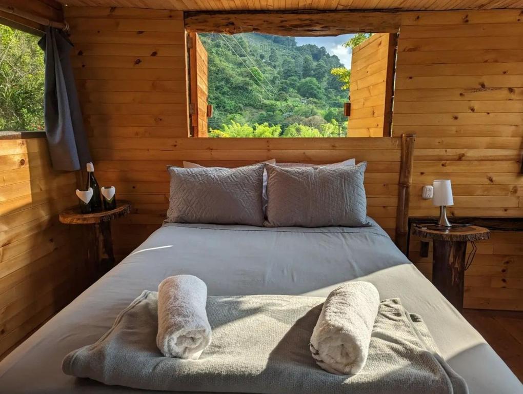 a bed in a wooden room with a large window at Habitación Colibrí, Pijao, Finca Flora del Río in Pijao