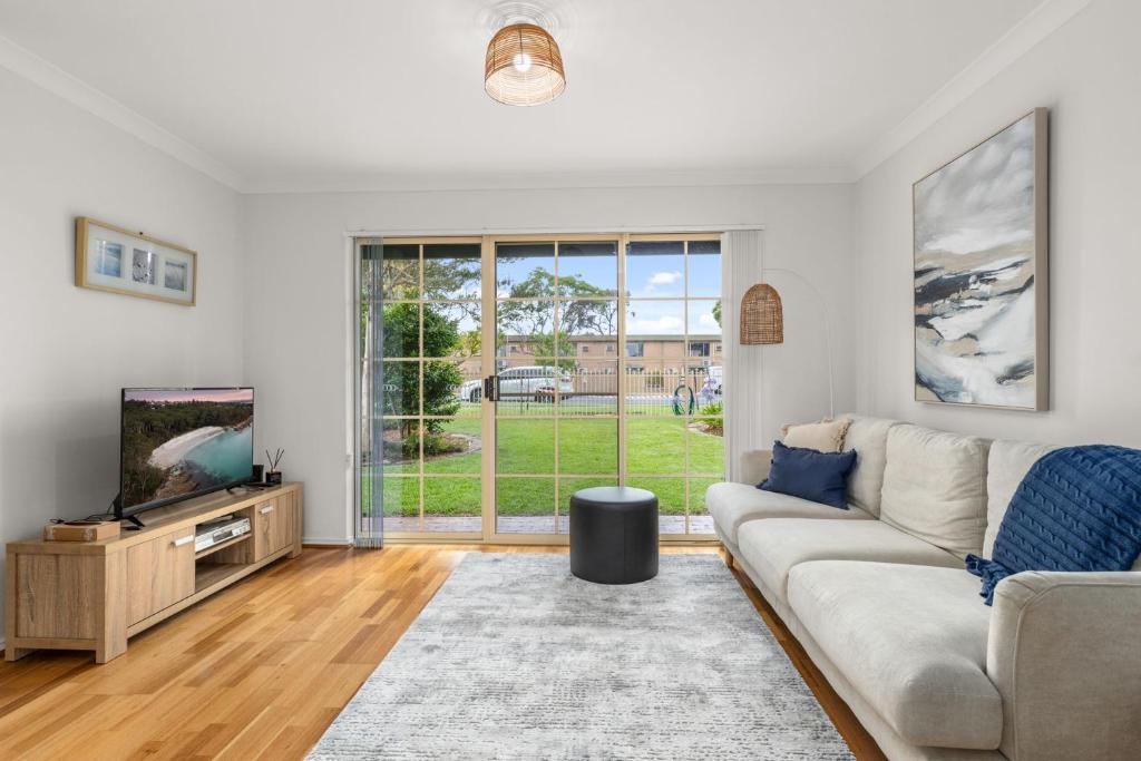a living room with a couch and a tv at Shells by Experience Jervis Bay in Huskisson