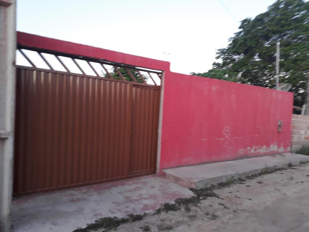 una cerca roja con una puerta roja y una acera en Porto apartamento 6, en Porto Seguro