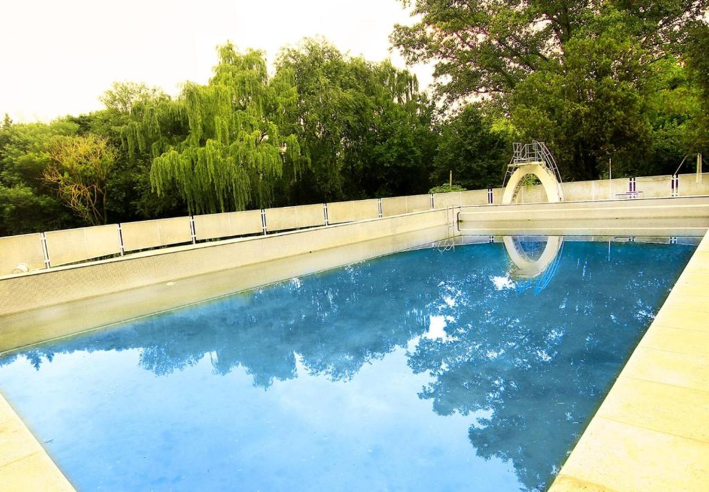 una piscina de agua azul con un puente y árboles en El Pinar en Bialet Massé