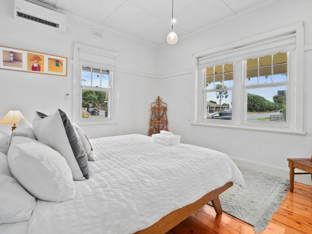 1 dormitorio blanco con 1 cama y 2 ventanas en Piper St Cottage, en Yarrawonga