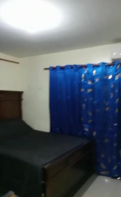 Habitación con cama y cortina azul en Recidencial Albolera en Cancino Adentro