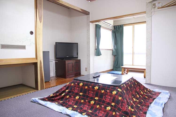 a living room with a bed and a tv at ロッヂとんや in Seki