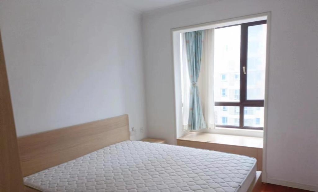 a white bedroom with a bed and a window at 新虹桥首府 in Shanghai