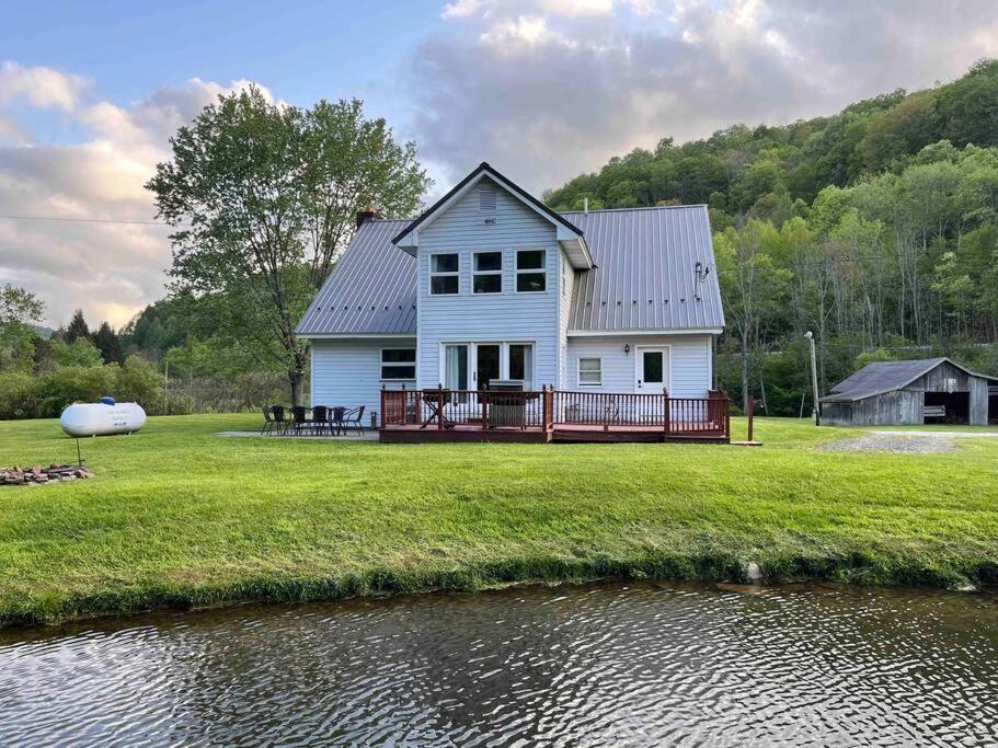 una casa blanca en un campo junto a un río en The Watson Farm, 
