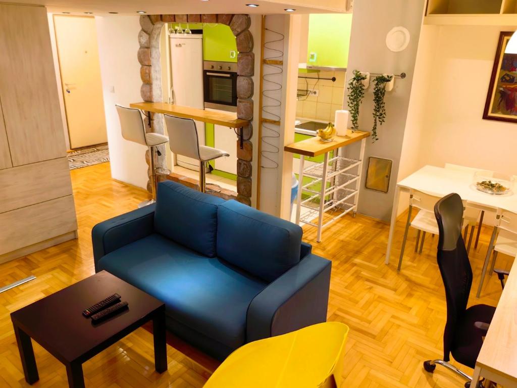 a living room with a blue couch and a kitchen at Apartman Stepa K3 in Belgrade