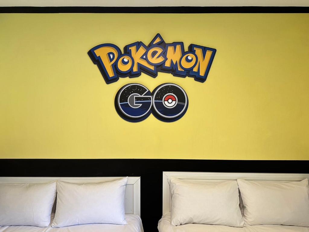 a yellow wall with a pokemon sign above two beds at 逢甲 Toy RooM in Taichung