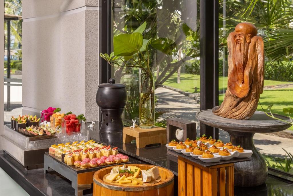 A selection of pastries, fruit and bite-sized dishes is arranged beside floor-to-ceiling windows.