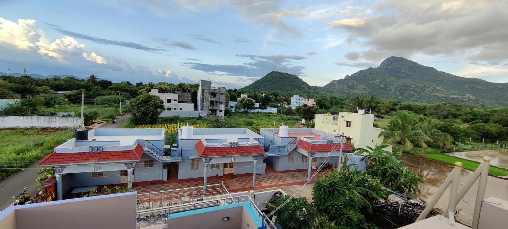 un edificio con techos rojos con montañas al fondo en ARUNACHALA HOUSES, en Tiruvannāmalai