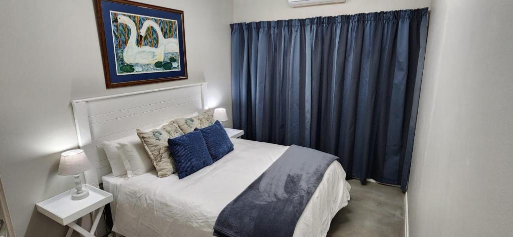 a bedroom with a large bed with blue curtains at Cottage Rose in Bloemfontein