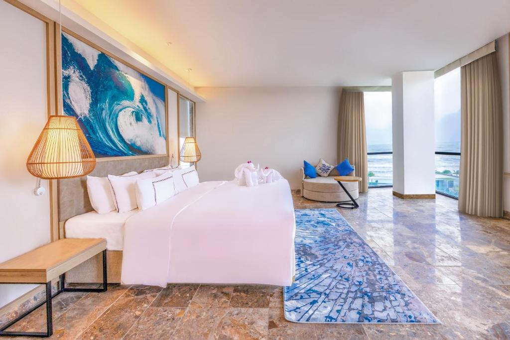 A bright guest room with a large bed, ocean-facing seating area, and contemporary tropical decor.
