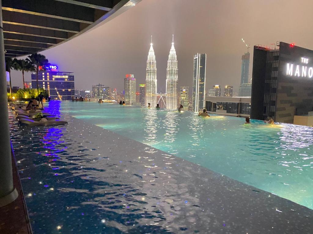 una piscina a sfioro con vista sullo skyline della città di notte di Eaton Residences at Leo a Kuala Lumpur