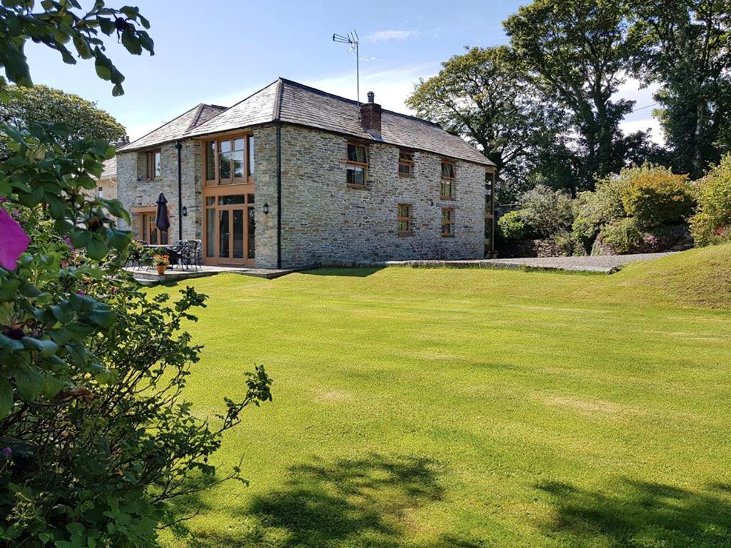 an old stone house with a large green yard at Polmear Barn in Camelford