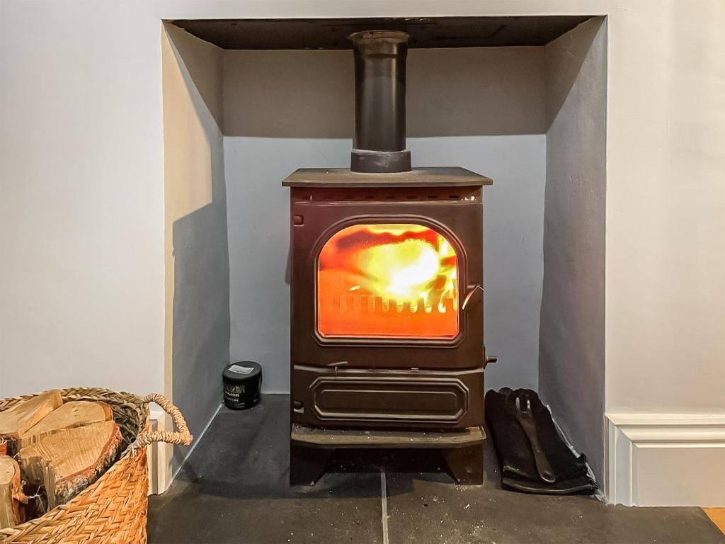 a wood stove with a fire in a room at Belle Vue in High Bentham