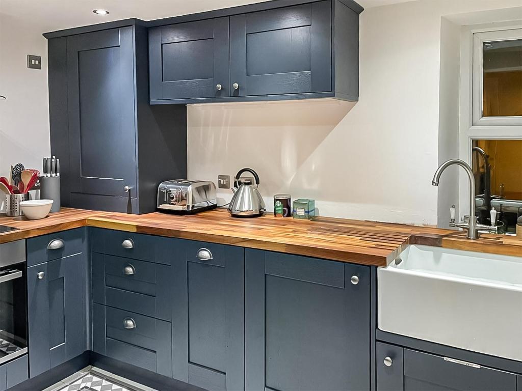 una cocina con armarios azul marino y fregadero en Belle Vue en High Bentham
