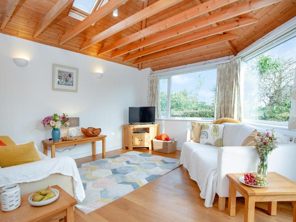 a living room with white furniture and wooden ceilings at Bay Tree in Porthscatho