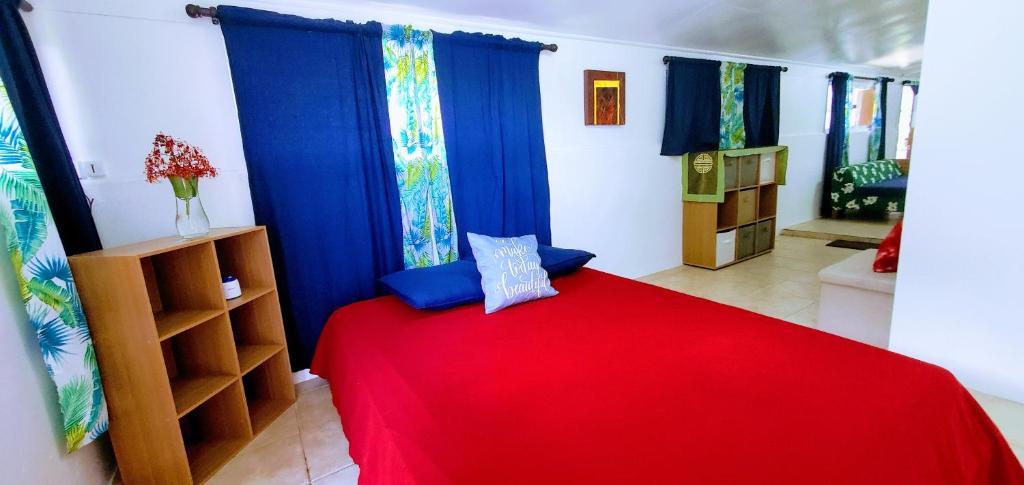 Schlafzimmer mit einem roten Bett und blauen Vorhängen in der Unterkunft Studio Nui 1 Room Fare Tepua Lodge in Uturoa