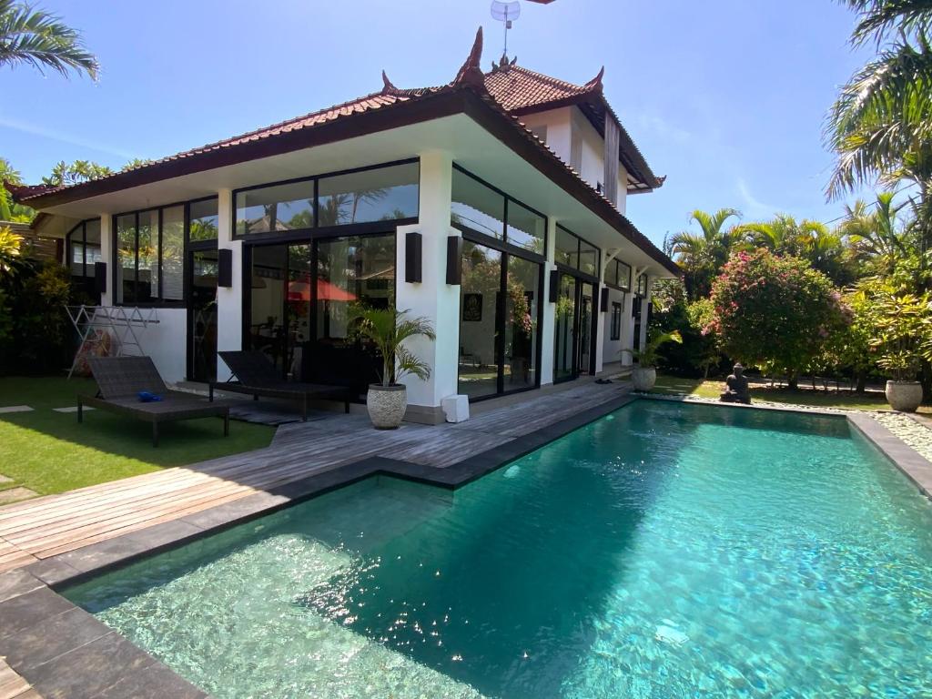 a villa with a swimming pool in front of a house at Villa Surga in Seminyak