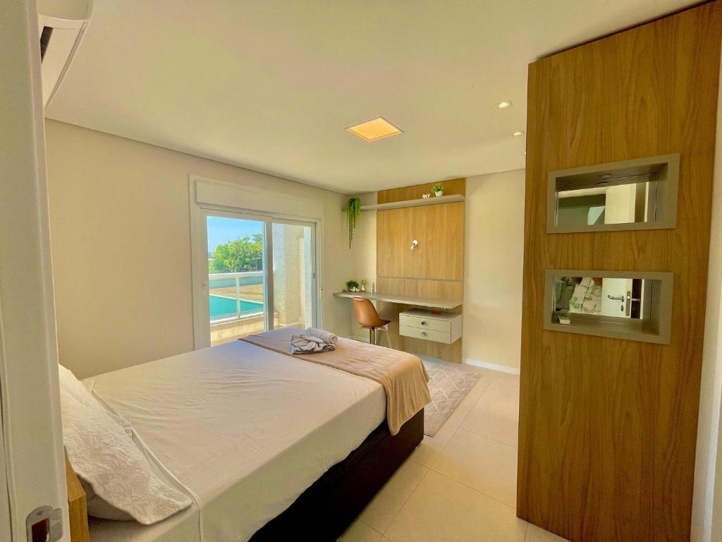 Schlafzimmer mit einem Bett, einem Fenster und einem Schreibtisch in der Unterkunft Atlântida Green Square - 408B in Xangri-lá