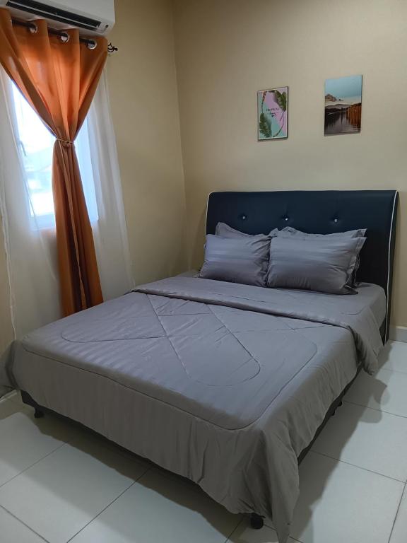 a bed with a blue headboard and a window at NURUL ROOMSTAY LANGKAWI in Pantai Cenang