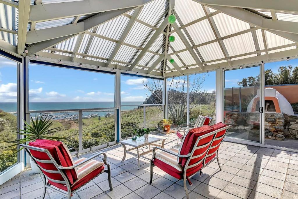 a patio with two red chairs and a table at The Darling Of Marina - A Hilltop And Sea Getaway in Wirrina Cove