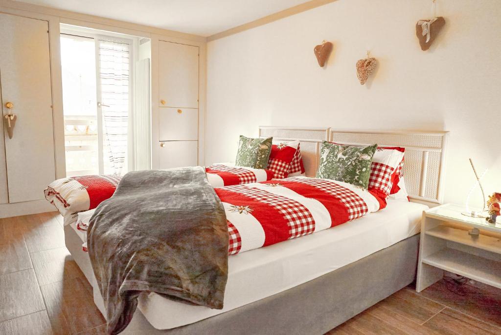 a bed with red and white blankets and pillows at Sweet Room by Interlaken in Därligen