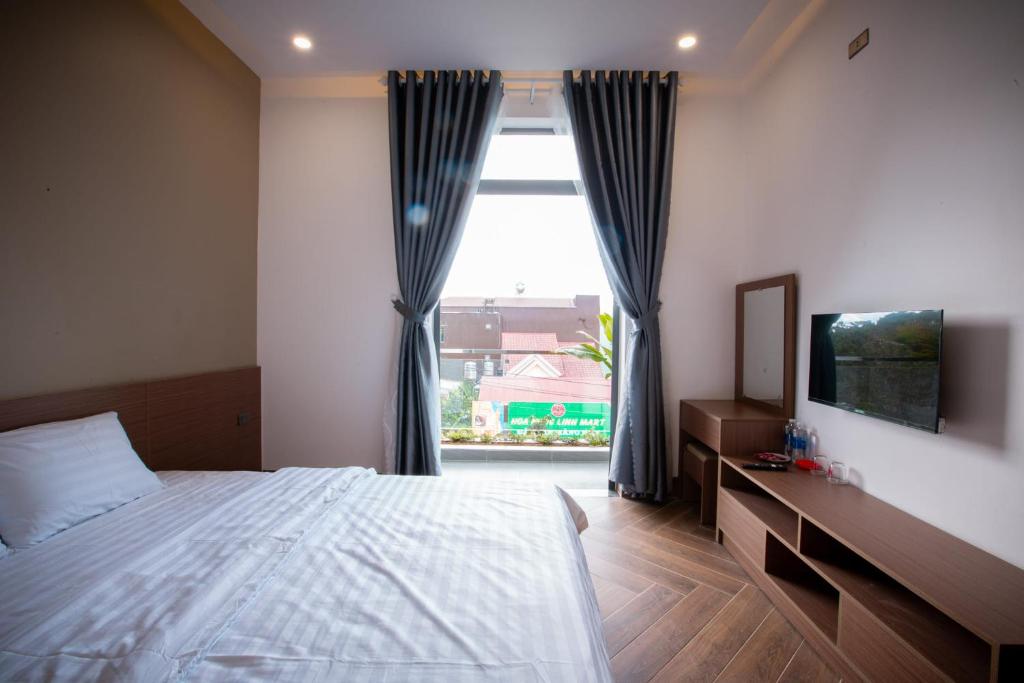 a bedroom with a bed and a large window at Khách sạn Mimosa in Kon Plong