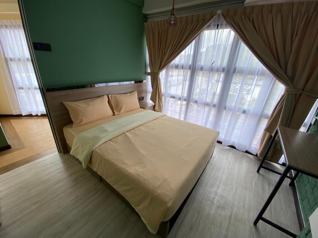 a bedroom with a bed with a green wall and windows at Clock Inn Backpackers Hostel in Tanah Rata